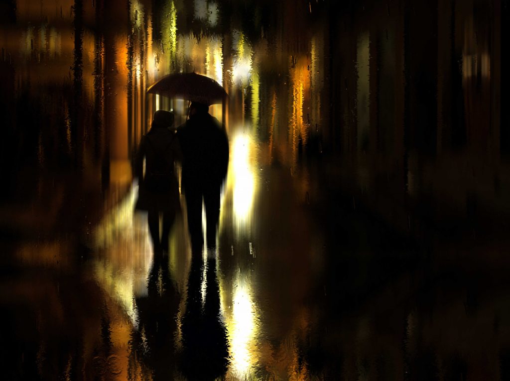 Twee mensen onder een paraplu in een donkere straat